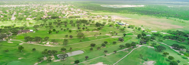 istock Panorama aerial view subdivision sprawl surrounding golf course community in Hazel Park, Corpus Christi, TX, residential houses swimming pool, country club sand trap, club cars pathway, fairway 2171131551