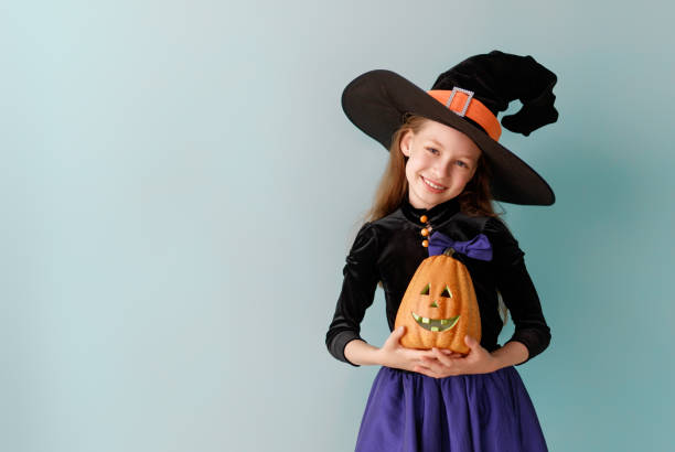 istock girl in witch costume with Halloween pumpkin 2171134963