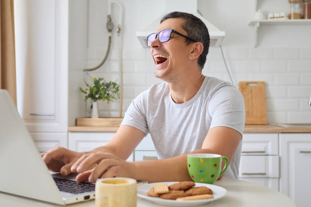 istock Funny man freelancer working on laptop while sitting at table laughing happily during digital education course and browsing web enjoying virtual connection and internet work environment at home 2171134967