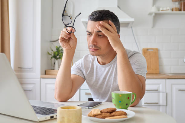 istock Young man freelancer taking off glasses using laptop feeling tiredness and suffering headache while thinking deeply about hid online project working from home in kitchen 2171134977