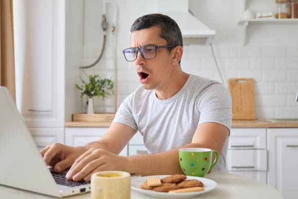 istock Scared surprised man freelancer using laptop with wifi connection working on career and education online shocked by problems while typing and browsing web posing in kitchen at home 2171134992