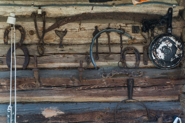 istock Old Slavic tools and tools hang on the wall of a log house 2171141299