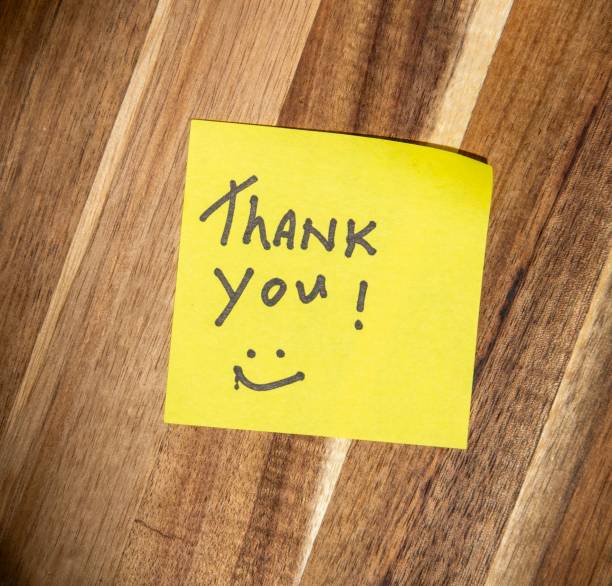 istock Yellow Thank You Post-it Note with a smiley face on a wooden background with copy space 2171146638