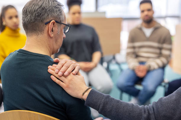 istock Senior man being comforted by another participant in group therapy at community center 2171148861