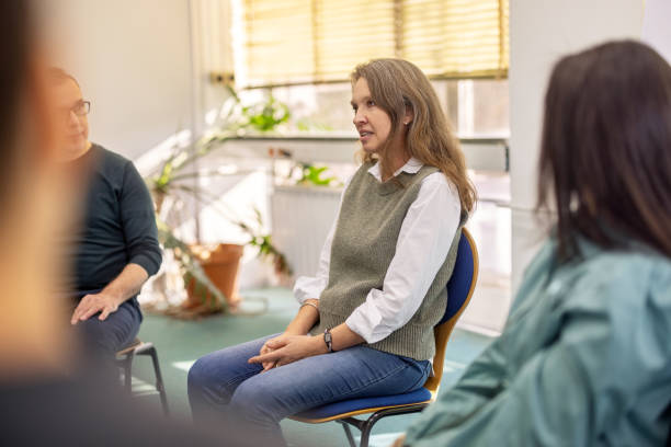 istock Mature woman talking about her experiences during a group therapy session 2171148884