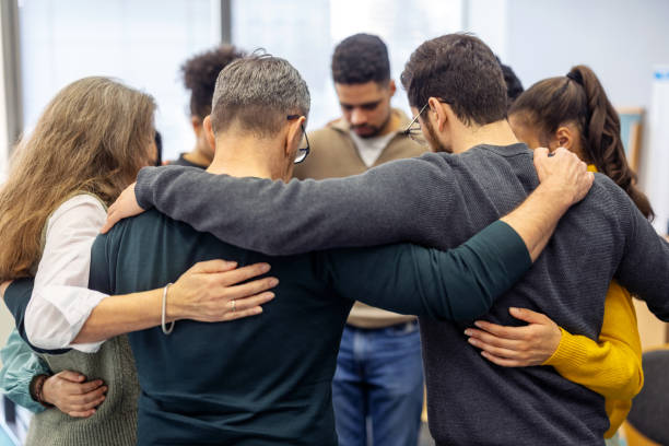 istock Diverse group of people standing in a circle with arms around each other 2171148923