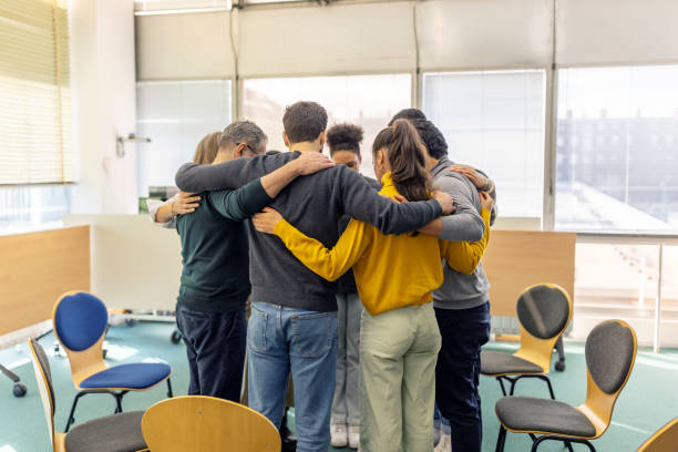 istock Support group in a huddle with arms around each other at community center 2171148929