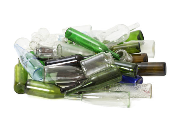Woman At Recycling Centre Disposing Of Glass Wine Bottles At Bottle Bank
