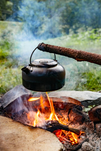 istock Making tea over an open fire in the forest. The kettle is hanging on a stick on the fire. 2171159161