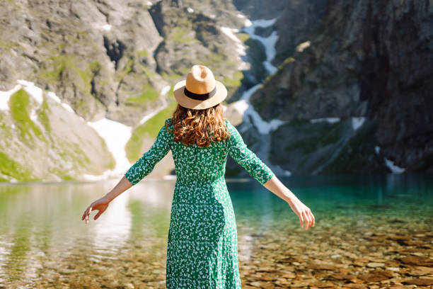 istock A woman strolls barefoot across smooth stones at a tranquil mountain lake. 2171164471