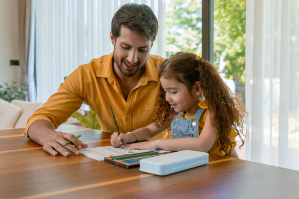 istock The father is sitting with his daughter in a modern home interior, emphasizing simplicity and a healthy lifestyle. The little girl is smiling happily while they both work on a colorful pencil drawing. 2171165408