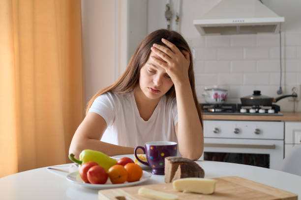 istock Distraught depressed Caucasian woman sitting at table in kitchen with leaning head on her hand looking at simple meal with sadness in her facial expression having no appetite 2171166727