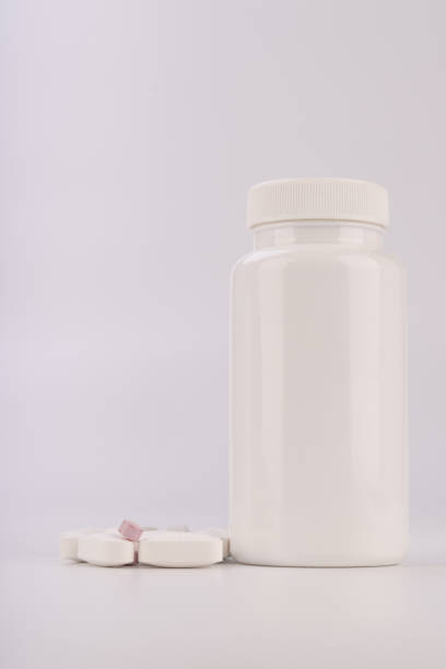 Pills cascading from a white plastic bottle on a clean white surface. Perfect for illustrating concepts related to medicine, health, and pharmaceuticals