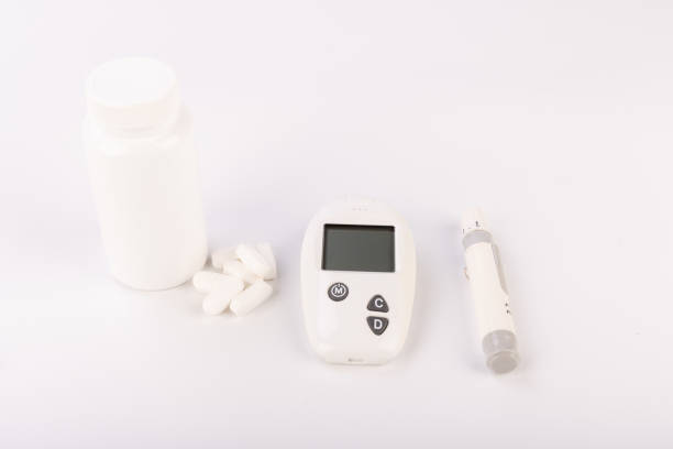istock White Pill Container Next to Glucose Testing Kit and Lancet on White 2171172170