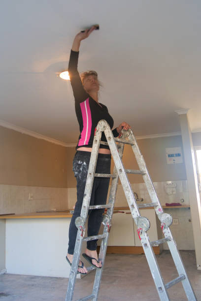istock Vertical image of Woman standing on a ladder and sanding a ceiling while doing home improvements. 2171173070