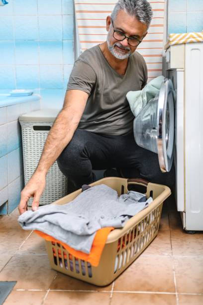 istock Mature man putting clothes into washing machine 2171178269