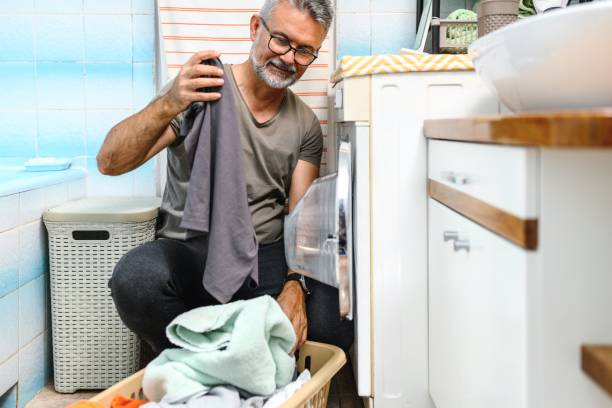 Mature man putting clothes into washing machine
