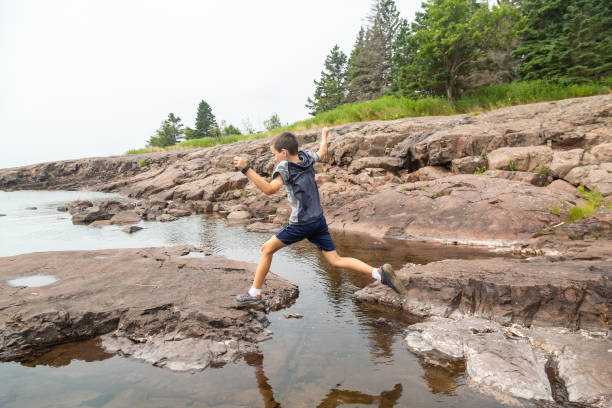 istock Boy Jumping From Rock to Rock 2171181910