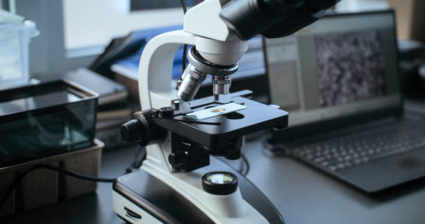istock Microscope with sample on glass slide and laptop standing on the table 2171182811