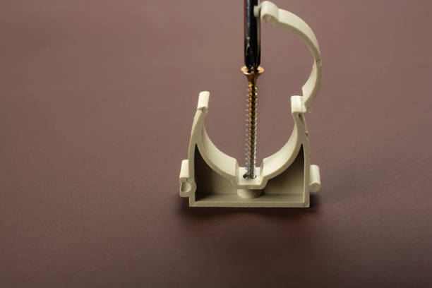 Fastening the plastic pipe clamp to the wall.