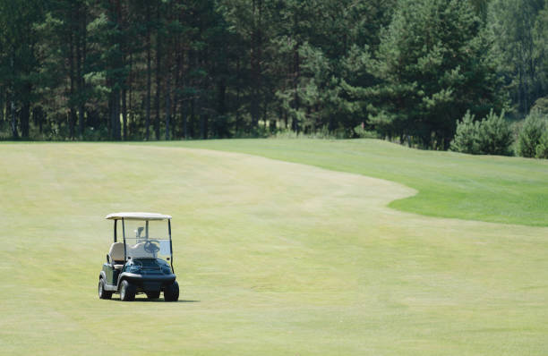 Golf cart drives around green course during day. Playing golf on a car