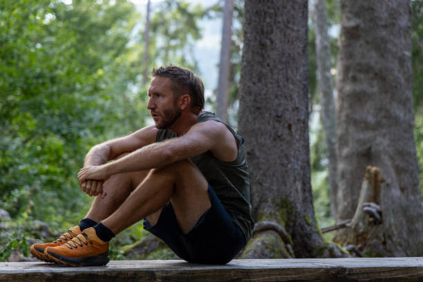 istock Man Resting on a Wooden Bench in the Forest Post-Workout 2171195284
