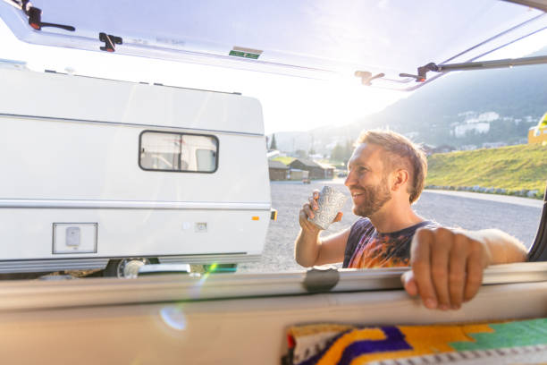 istock Man enjoying coffee outside camper van in the morning sun 2171200667