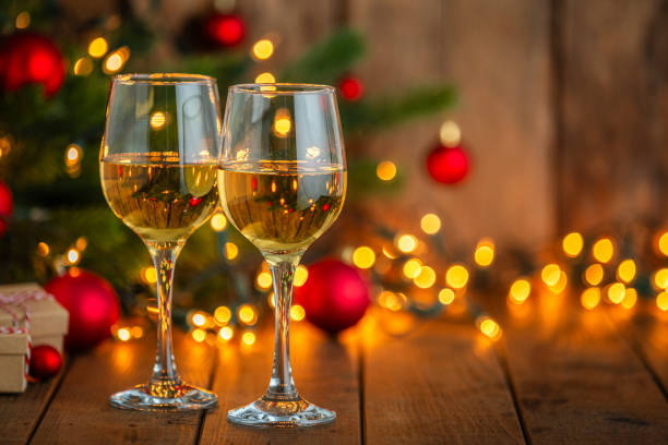 istock Two white wine glasses on Christmas dining table. Defocused lights at background 2171200818