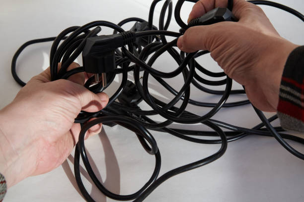 istock Hands trying to untangle tangled black electrical wires, tangled wires in hands, close-up on a white background 2171201152