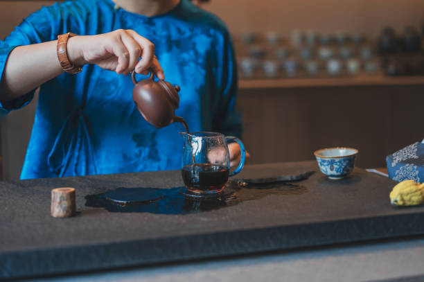 istock Tea being poured from a teapot into a glass pitcher by a person in blue. 2171202896