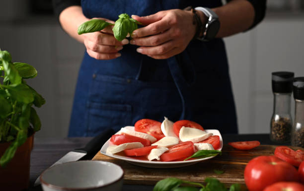 istock Woman Decorating A Caprese Salad With Basilic In The Kitchen 2171204810
