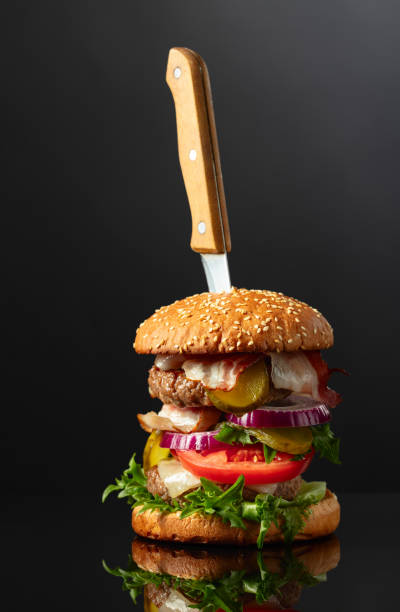istock Burger with knife on a black reflective background. 2171205878