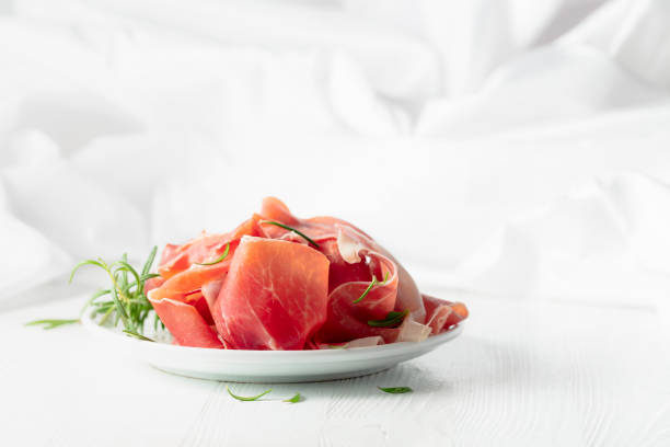 istock Prosciutto with rosemary on a white wooden table. 2171205939