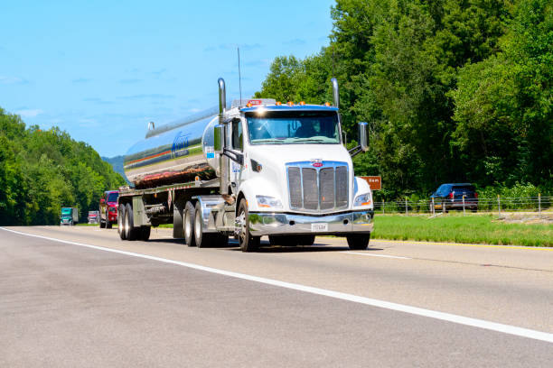 Knoxville, Tennessee, United States  August 20, 2024: Horizontal shot of a petroleum carrier tanker truck changes lanes on an interstate highway. Heat waves rising from the hot asphalt creates a blurring effect on background trucks and foreground pavement.