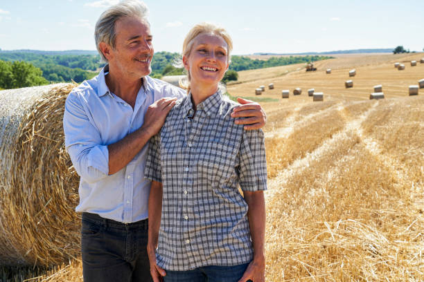 istock Farmer and wife standing harvested field next hay bale rolls after a long work day 2171217112