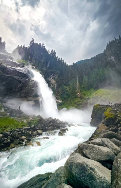 The bottom falls of Krimml Falls with heavy flow of water on a dark day just before a storm.