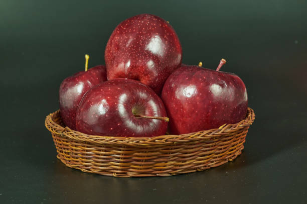 Fresh red apple fruit in basket on green background still life