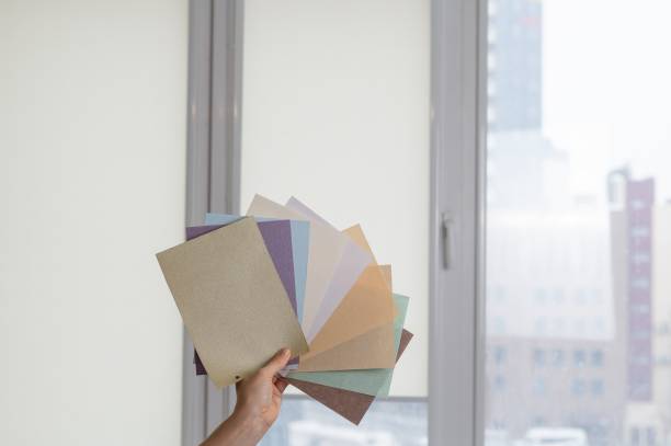 istock Woman holding fabric samples of roller blinds against window background. 2171223678
