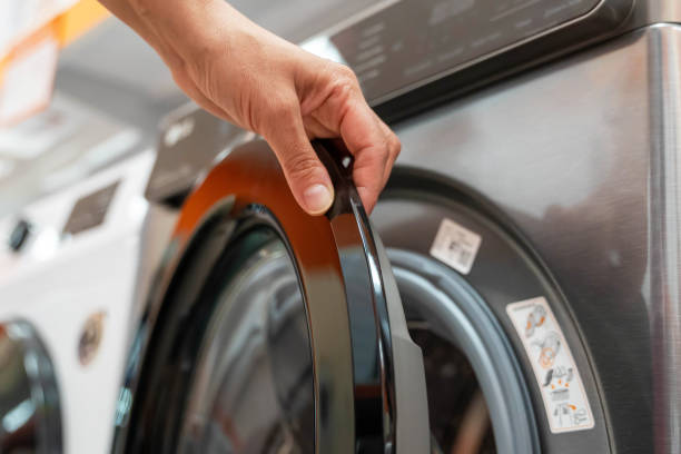 istock A hand reaches out to open a modern washing machine door 2171226225