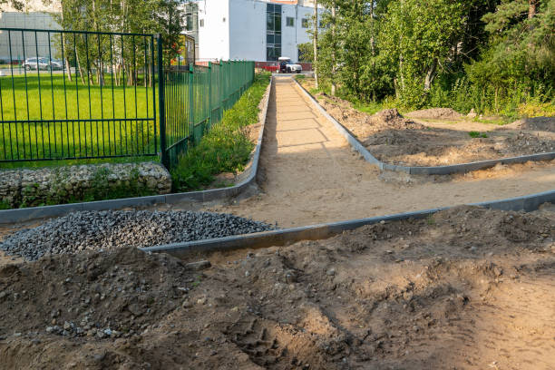 A construction site shows a pathway being built with gravel and sand