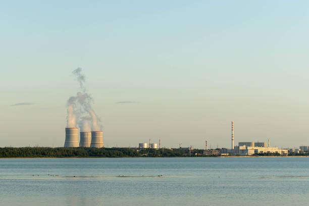 istock Cooling towers release steam while industrial facilities line the shore 2171226376