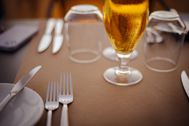 istock Blond golden beer served in a drinking glass on a served silverware table on brown palette, close up still 2171230354