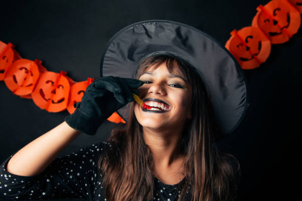 Funny little Halloween witch eating a worm shaped gummy