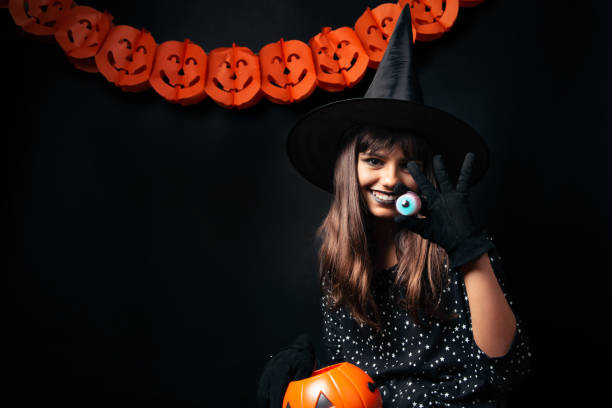 istock Happy young beautiful Halloween witch showing an eye shaped candy 2171234188