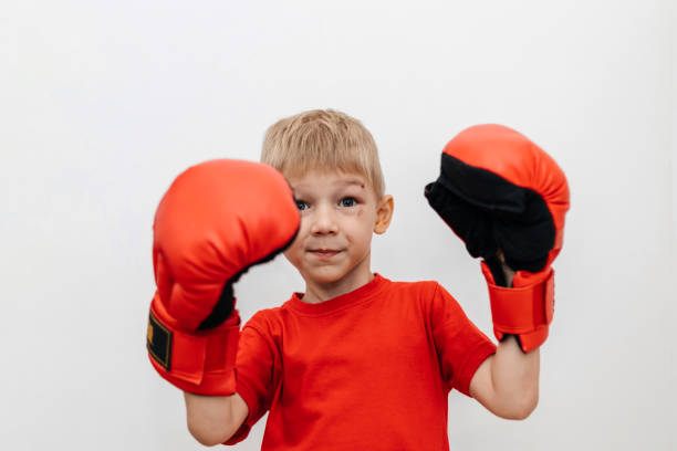 istock Boy in red boxing gloves on a white background with a scratch on his face. Protection. Self-defense 2171238196