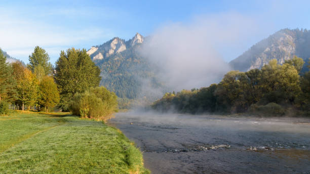 Three Crowns summit emerging from the morning fog. View from the bank of Dunajec river in Sromowce Nizne. Pieniny mountains, Poland