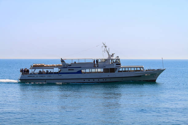 A pleasure steamer sails on a calm, smooth sea. In the background is a blue sky. Excursion tourism. Yalta, Crimea