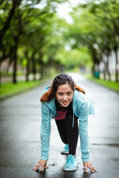 istock A young woman preparing for a run on a pathway lined with green trees 2171258959