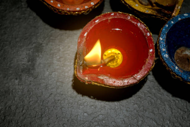 A row of small red and blue candles are lit, creating a warm and inviting atmosphere. The candles are arranged in a circle, with one of them having a larger flame, drawing attention to it. Diwali concept