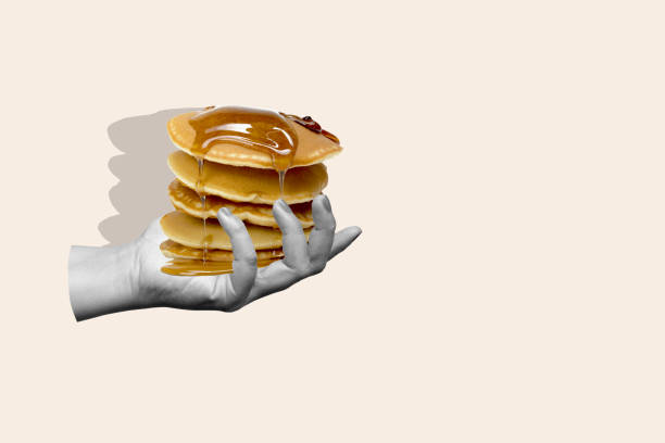 istock A hand holding a stack of pancakes with syrup dripping from them 2171261711